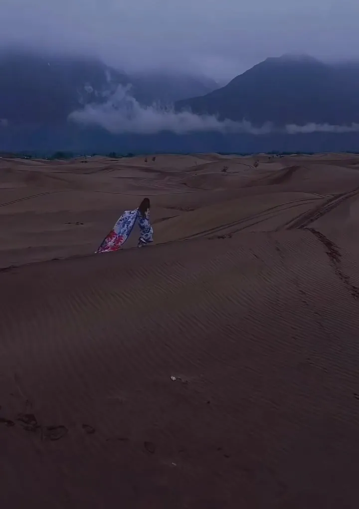 A traveller on the sand dunes with mountains behind